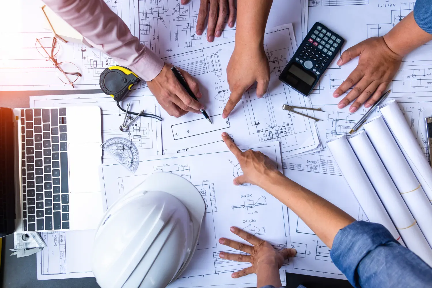 Ingenieure zeigen auf Gebäude auf Blaupause und mit Laptop zu zeichnen Design Gebäude Projekt im Büro, Bau-Konzept. Ingenieur Konzept